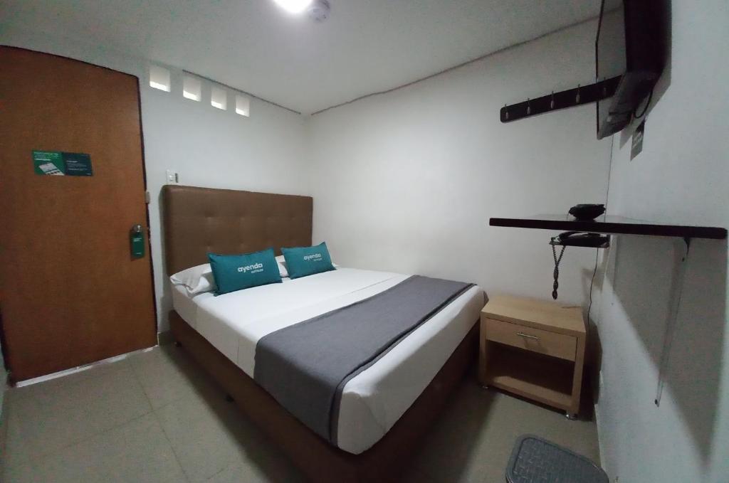 1 dormitorio con 1 cama con 2 almohadas azules en Ayenda Colombia Avenida, en Medellín