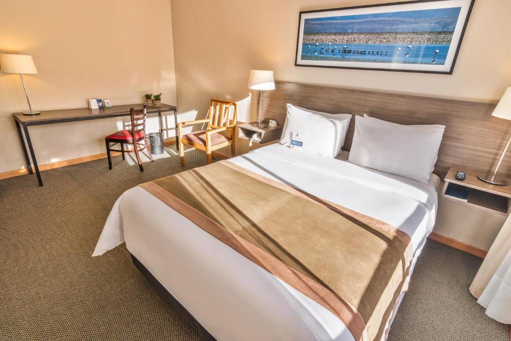 a hotel room with a large bed and a desk at Geotel Calama in Calama