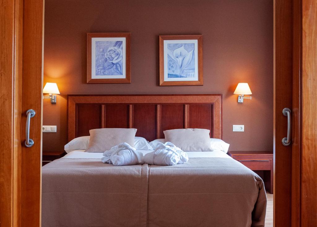 レオンにあるARVA Santiago Leónのベッドルーム1室(壁に2枚の写真が飾られたベッド1台付)