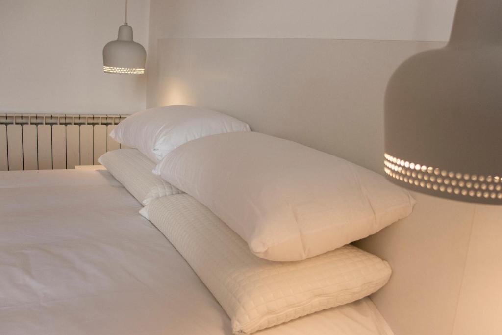2 almohadas blancas encima de la cama en Apartamentos Lucio Rodinso 