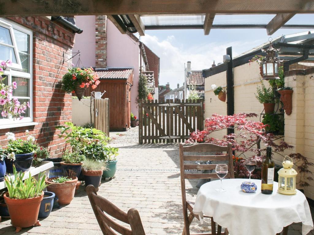 a patio with a table and chairs and potted plants at Northgate Bakery Annex in Beccles