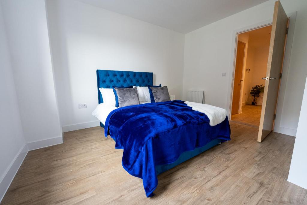 a bedroom with a bed with a blue headboard at Newly Built Spacious Apartment easily accessible to Luton Airport, Town centre and station in Luton