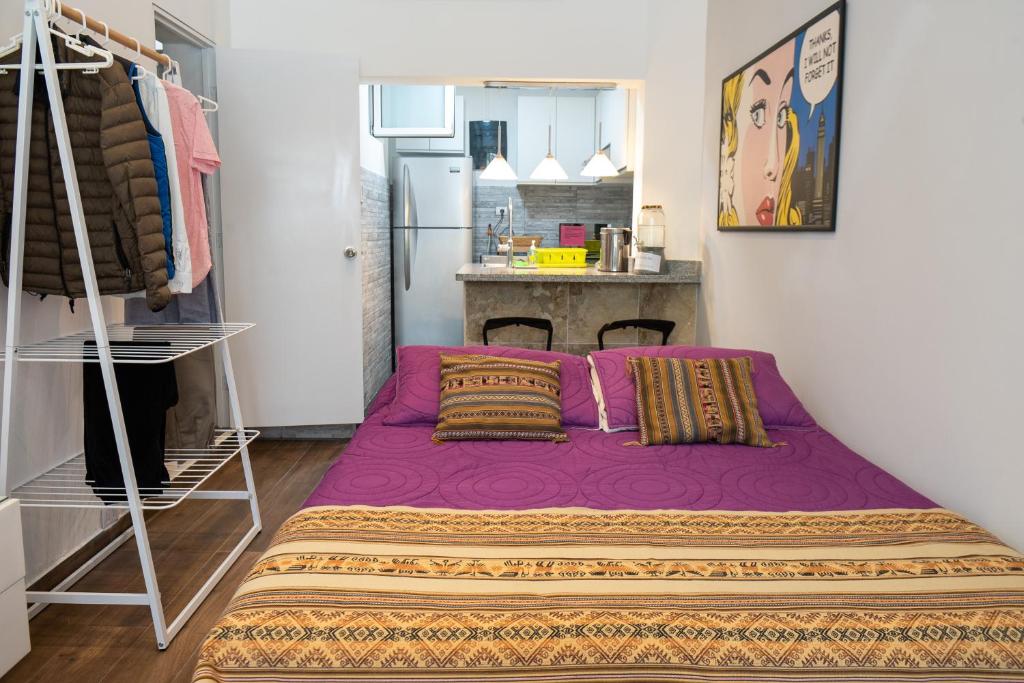 uma cama roxa num quarto com uma cozinha em Departamento Loft en Olivar de San Isidro em Lima