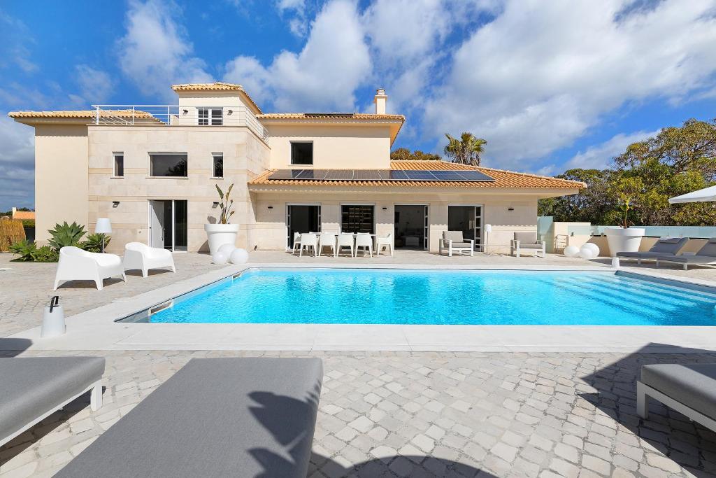 a villa with a swimming pool in front of a house at Soltroia Beach Court Villa in Troia