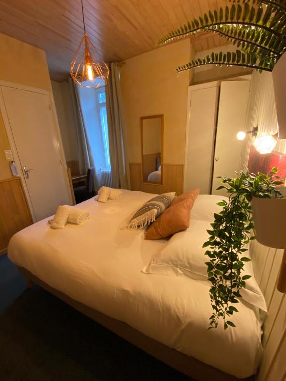 a bedroom with a large white bed with a plant on it at Hôtel Restaurant "La Petite Auberge" in Bourg-Saint-Maurice