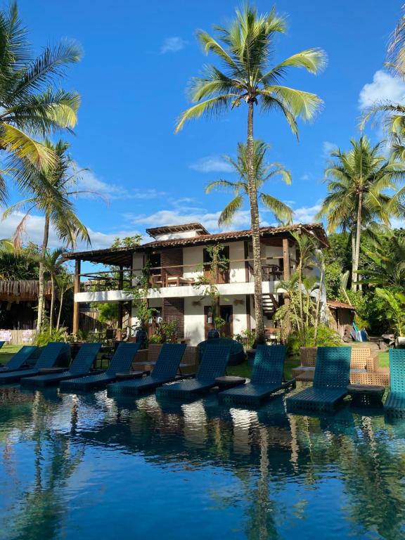 um resort com palmeiras e cadeiras na água em Pousada Casa da Praia em Caraíva