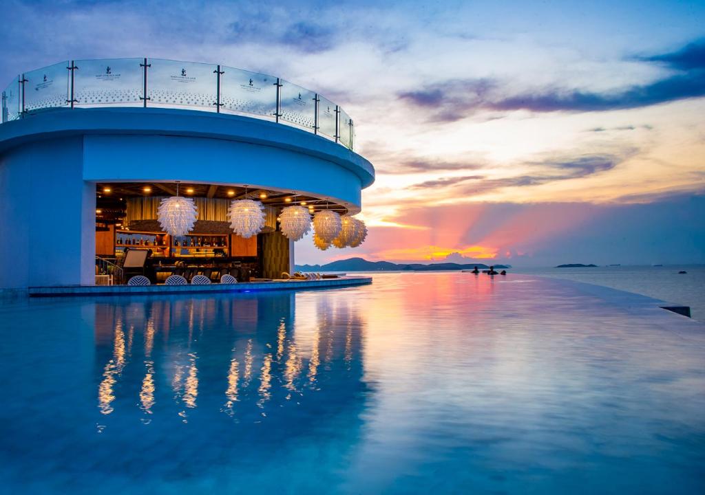 un edificio sobre el agua con una puesta de sol en el fondo en Royal Cliff Beach Terrace Pattaya en Pattaya South