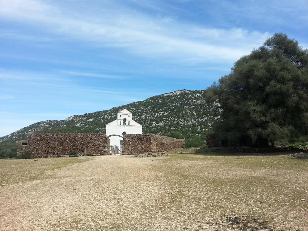 an old brick building with a mountain in the background at B&B Antico Telaio in Santa Maria Navarrese
