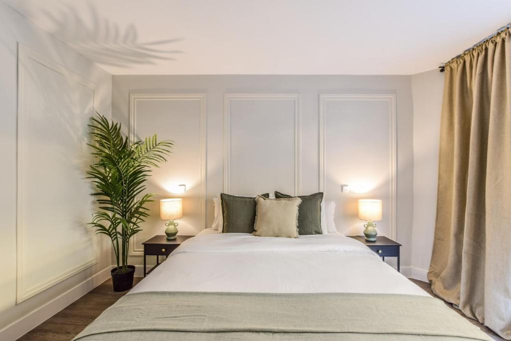 una camera da letto con un grande letto bianco con due lampade di AmazINN Places Gran Via VII a Madrid