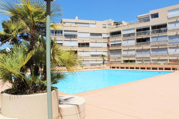 une piscine en face d'un grand bâtiment dans l'établissement Le Zodiaque 20m2 piscine, à Hyères