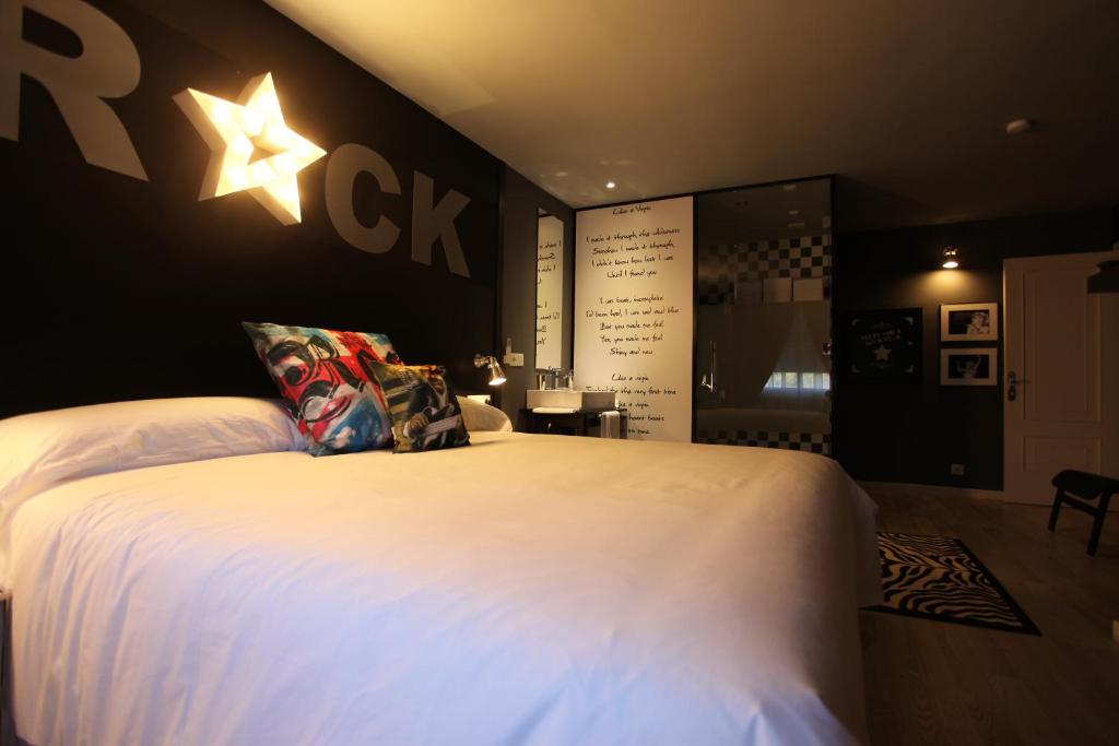 ein Schlafzimmer mit einem großen weißen Bett mit einem Stern an der Wand in der Unterkunft Hotel Apartamentos Rock Star in Taboadela