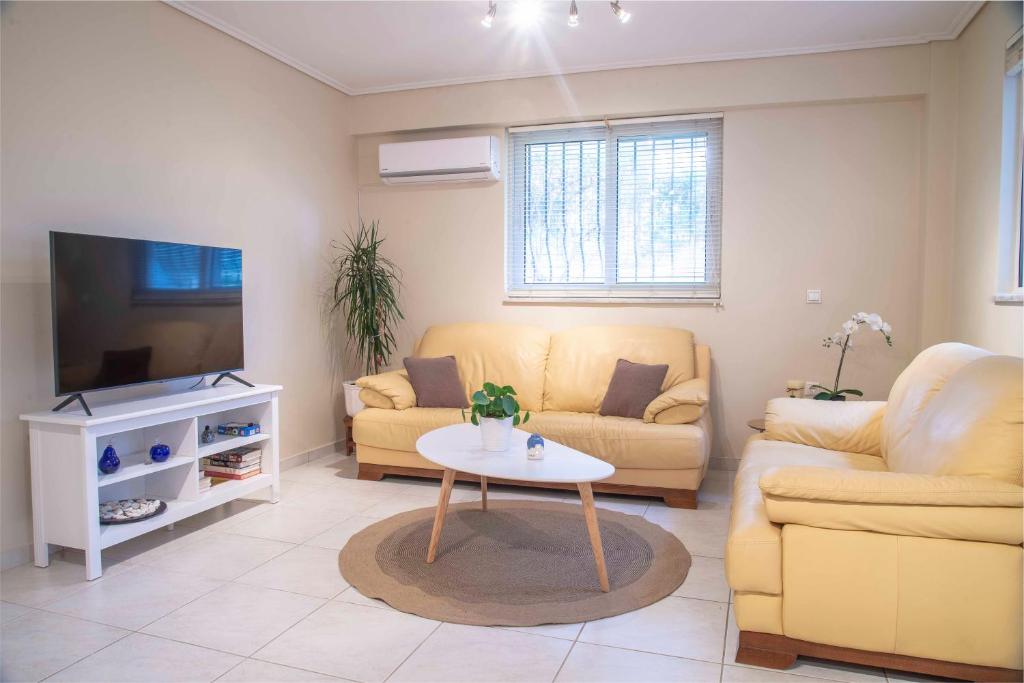 uma sala de estar com um sofá, uma mesa e uma televisão em Cozy Beach Home Near Pristine Sea w/ Free Netflix em Nea Makri