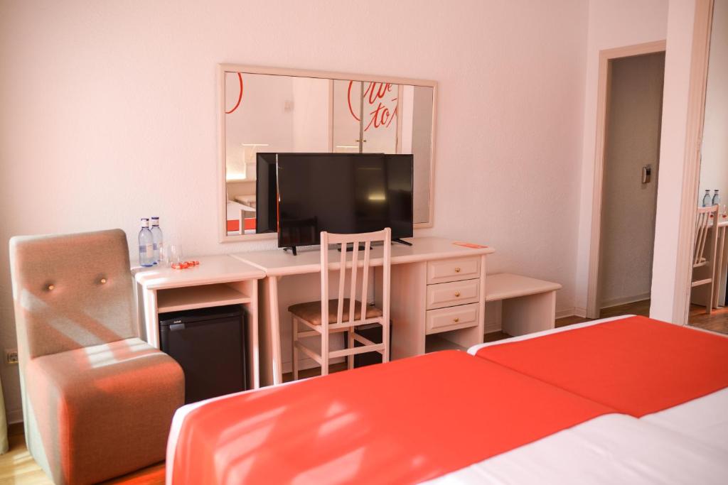 a bedroom with a desk with a television and a bed at Lloret Vibe Affiliated by FERGUS in Lloret de Mar