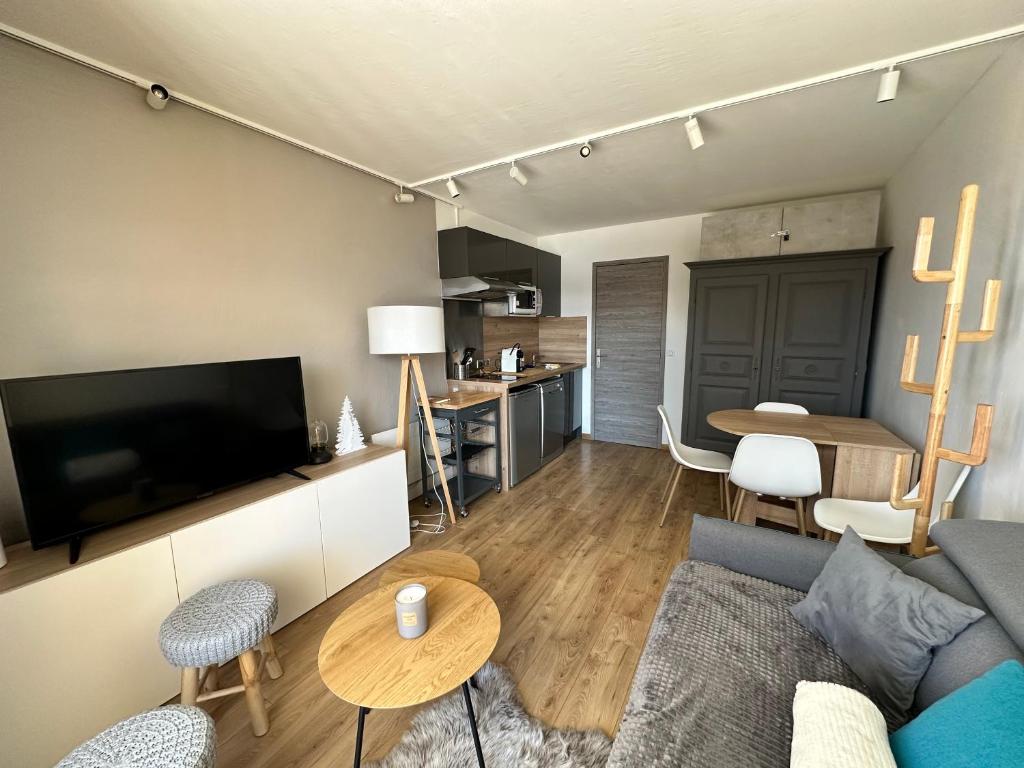 a living room with a couch and a tv at charmant studio à la Rosière in Montvalezan