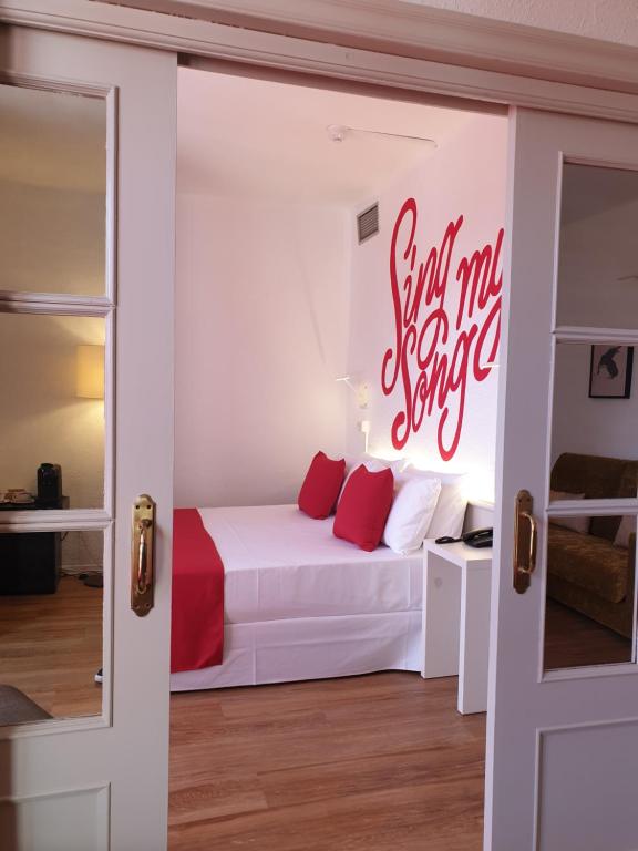 a bedroom with a white bed with red writing on the wall at Lloret Vibe Affiliated by FERGUS in Lloret de Mar