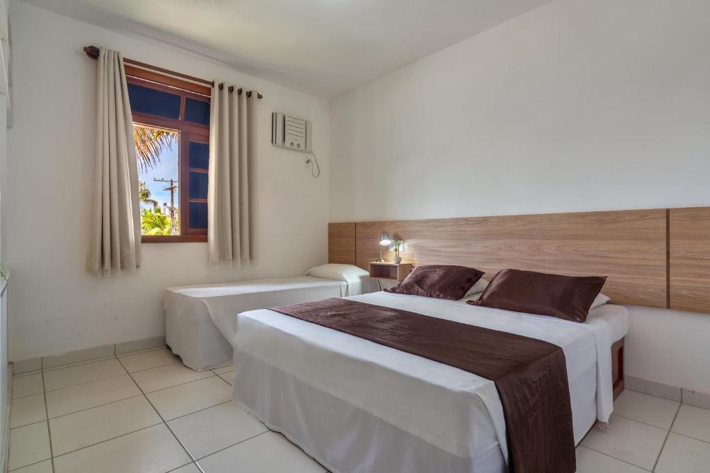 a hotel room with two beds and a window at America Praia Flat - Portal Hotéis in Porto Seguro