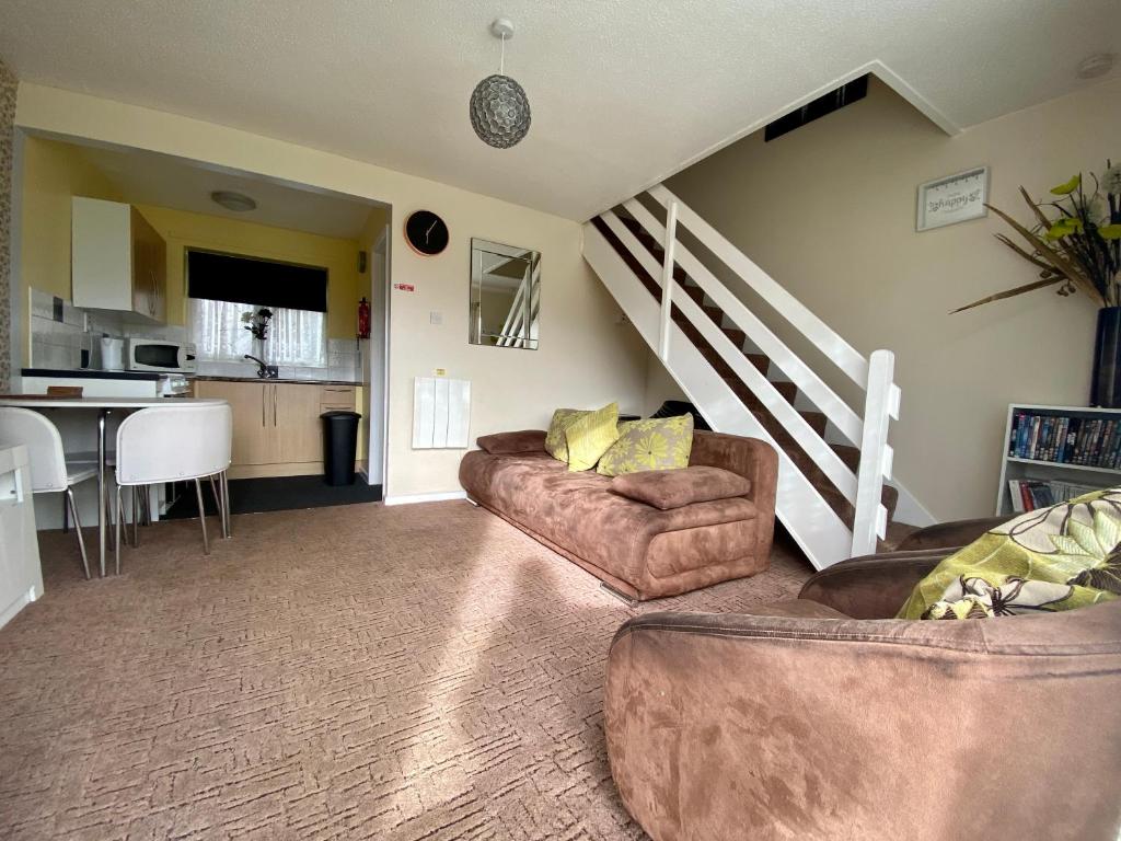 a living room with two couches and a staircase at Cosy and Comfortable Holiday Chalet 10 minutes walk to the beach, Norfolk in Great Yarmouth