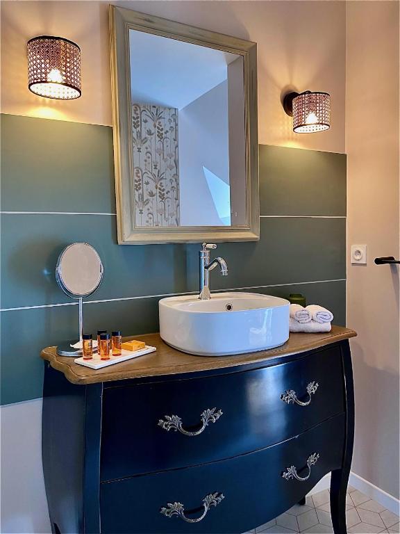a bathroom with a sink and a mirror on a dresser at Maison Alfred et Agatha in Pleudihen-sur-Rance
