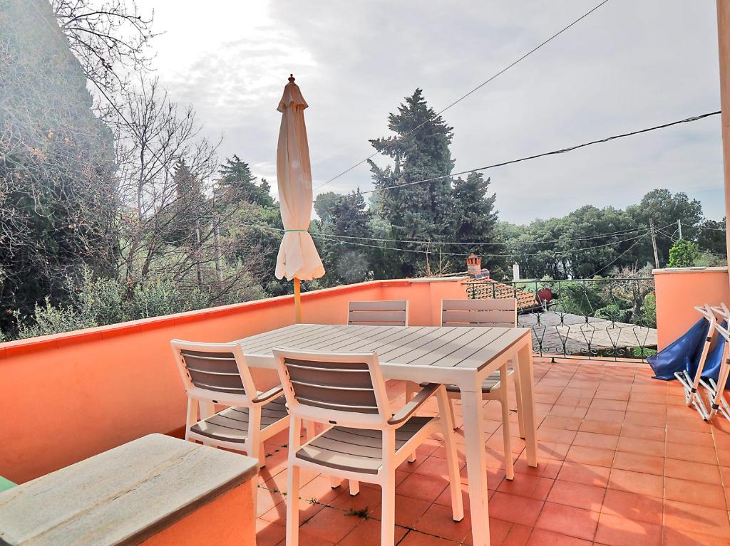 einen Tisch und Stühle auf einem Balkon mit Sonnenschirm in der Unterkunft Tra gli Ulivi e il Mare in Tellaro