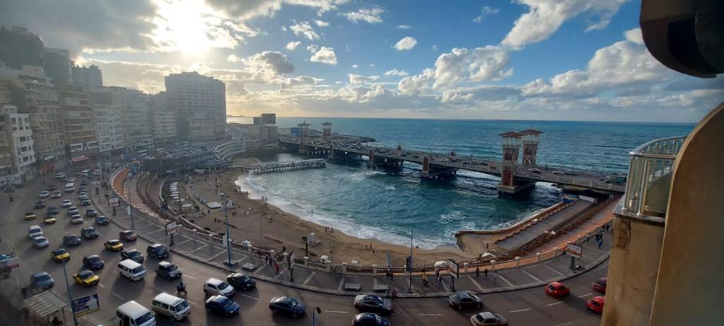 une rue urbaine animée avec des voitures et un pont sur l'océan dans l'établissement ستانلي اسكندريه, à Alexandrie