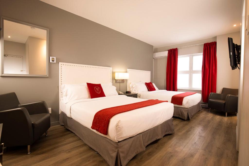 two beds in a hotel room with red curtains at Hotel du Nord in Quebec City