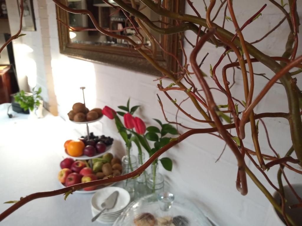 a table with a plate of fruit and a vase with branches at Hotel Stare Miasto Old Town in Poznań
