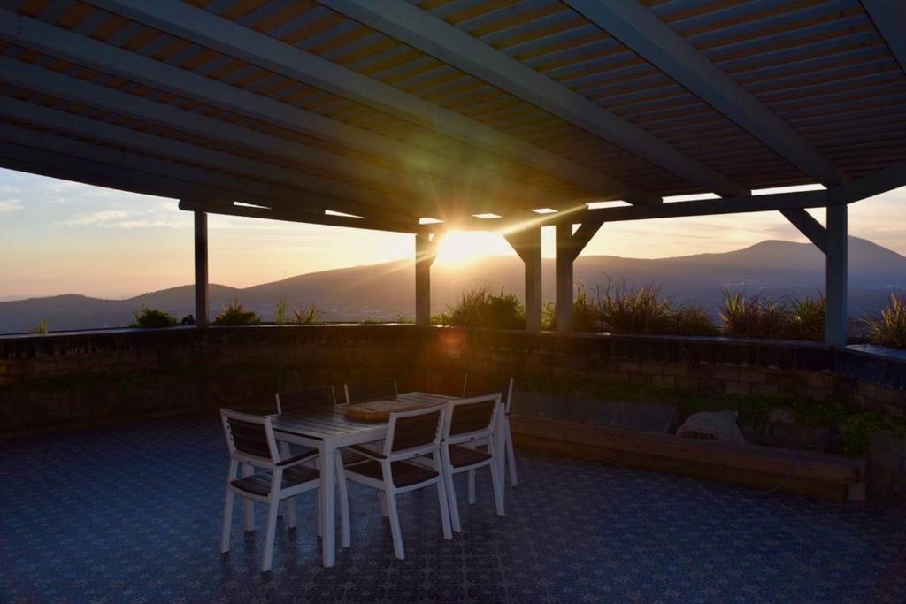 een tafel en stoelen op een patio met uitzicht op de zonsondergang bij The Royal Suite in Safed