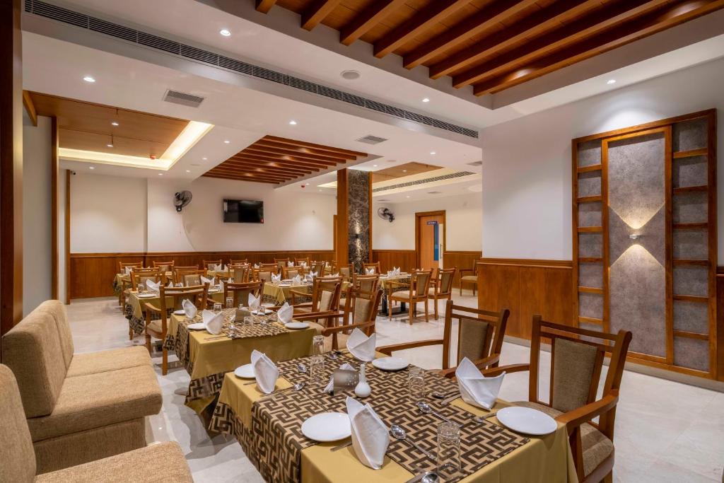 a restaurant with tables and chairs in a room at Hotel Panoramic in Ernakulam