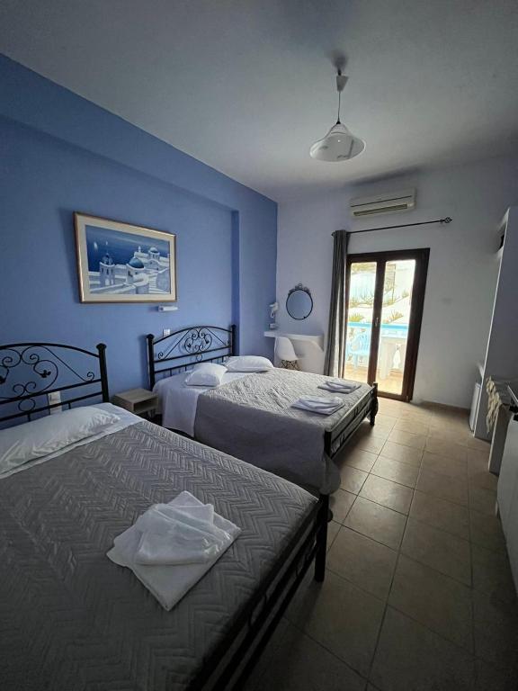 duas camas em um quarto com paredes azuis em Stella Nomikou Apartments em Firostefani
