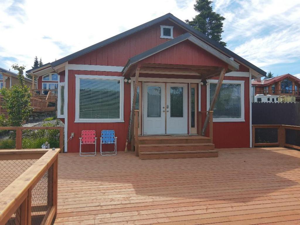 a red house with a deck with two chairs at Waterfront Cabin - Homer Seaplane Base in Homer