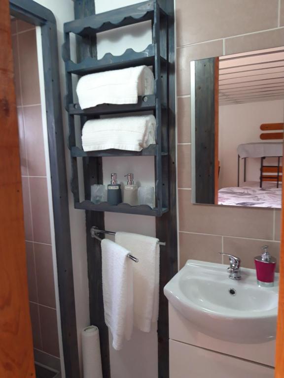 a bathroom with a sink and a mirror and towels at Alojamento Raminho dos Açores in Angra do Heroísmo