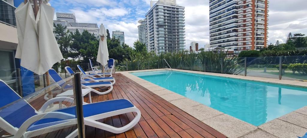 a swimming pool with chairs and umbrellas at Jose Luis Arenas del Mar Torre 1 in Punta del Este