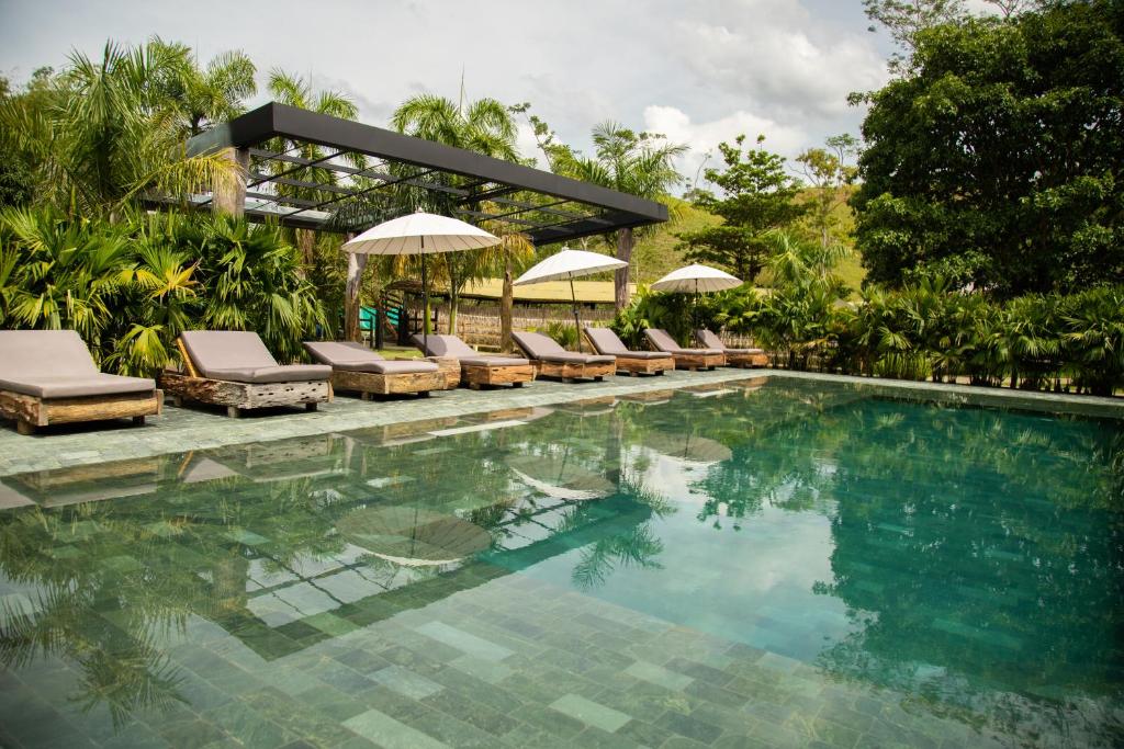 a swimming pool with chairs and umbrellas next to a resort at El Rio Hotel in Doradal