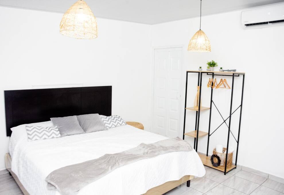 a white bedroom with a large bed and two pendant lights at Habitación Deluxe Aire - Villa Valle Campo 