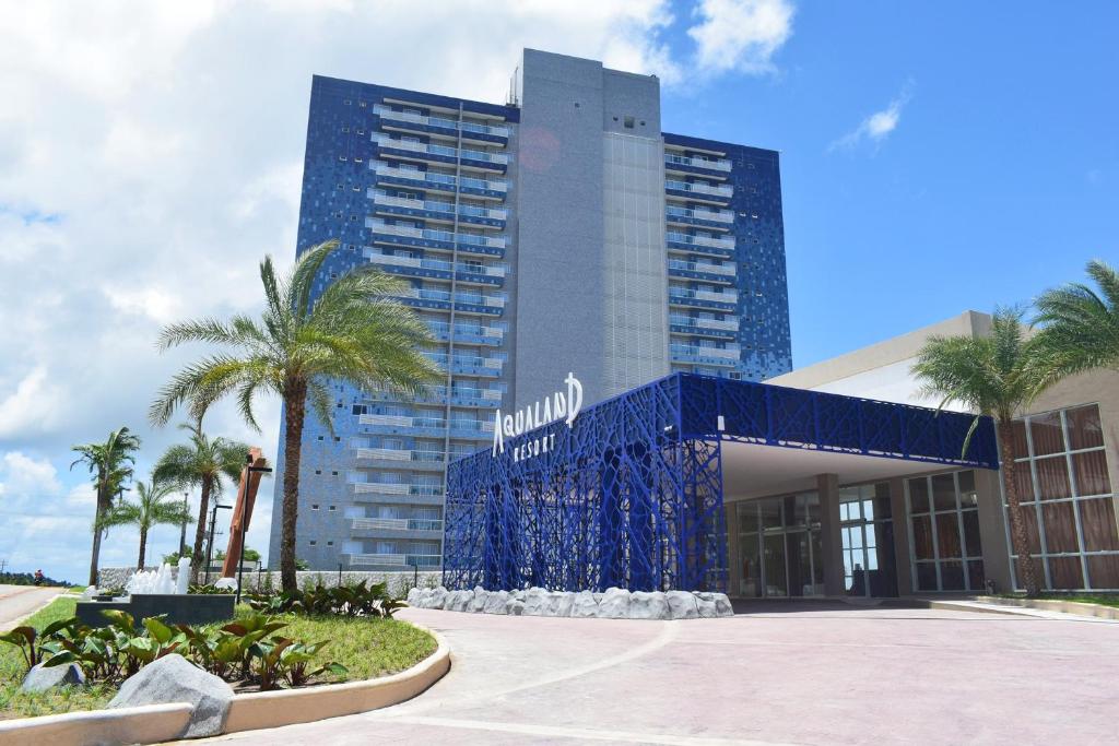 un edificio de hotel con una fachada azul y palmeras en Aqualand Park & Resort Oficial en Salinópolis