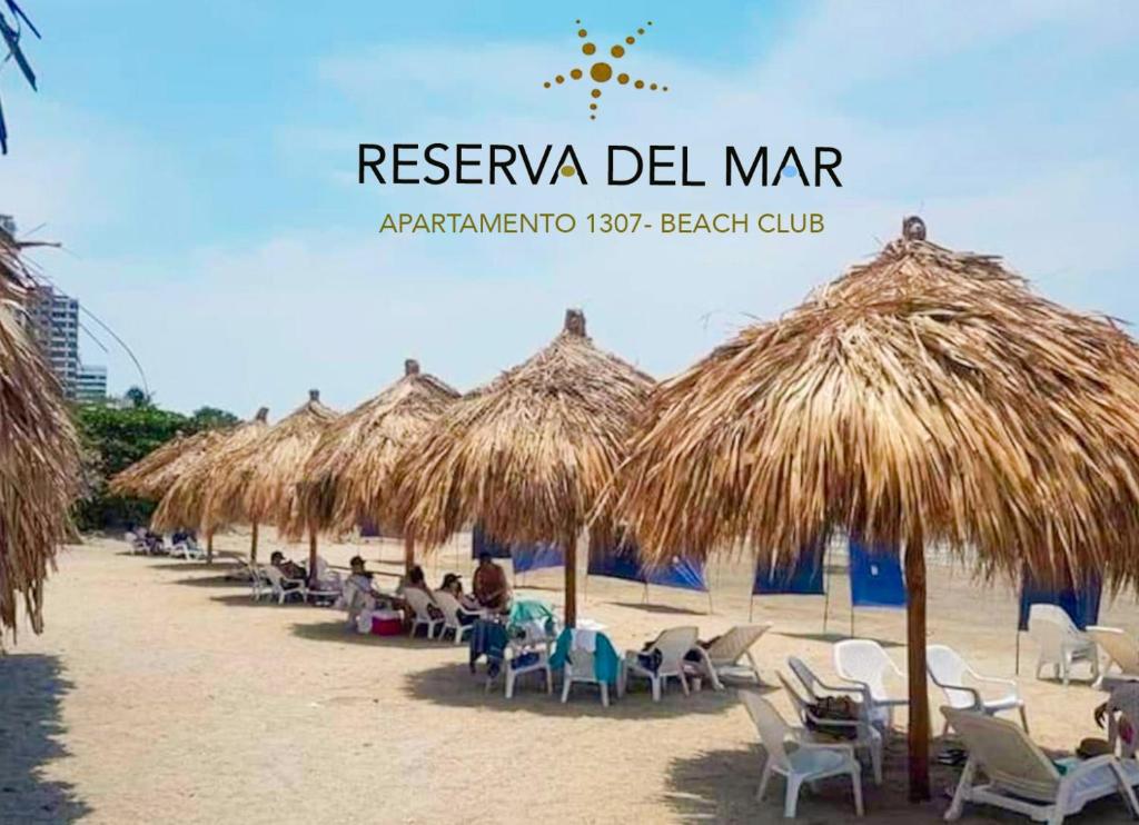 - un groupe de chaises longues et de parasols en paille sur une plage dans l'établissement Moderno Apartamento Salida directa al Mar Club de playa, à Santa Marta