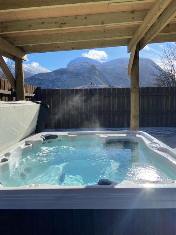 a hot tub under a pergola with mountains in the background at Victoria House Bed and Breakfast in Fort William