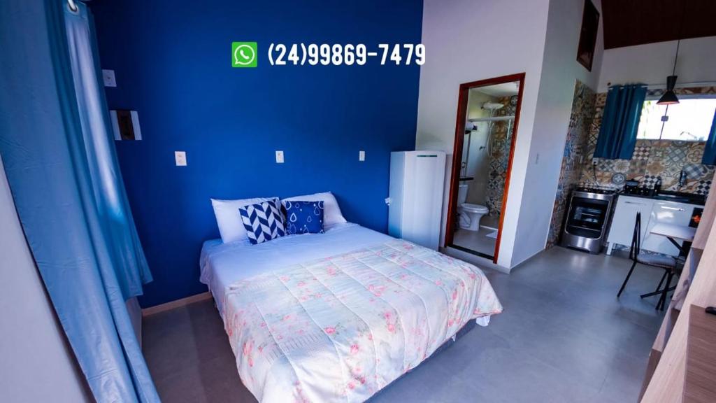 um quarto com uma parede azul e uma cama em Flats 1 Locação Penedo RJ em Penedo
