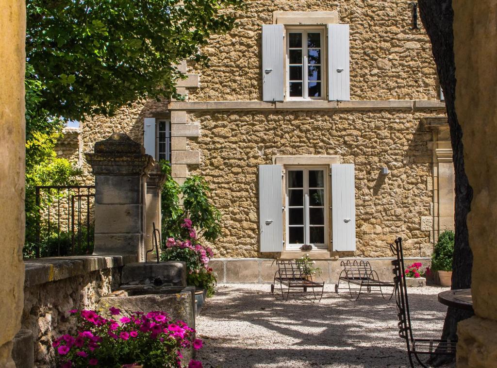 a stone house with white windows and pink flowers at La Moutière in Colonzelle