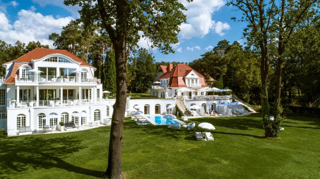 uma grande mansão branca com um telhado vermelho em Villa Contessa - Luxury Spa Hotels em Bad Saarow