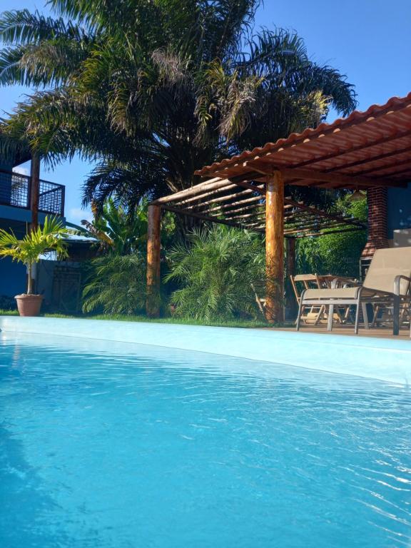 a swimming pool with a house and palm trees at Vila Itacimirim in Itacimirim