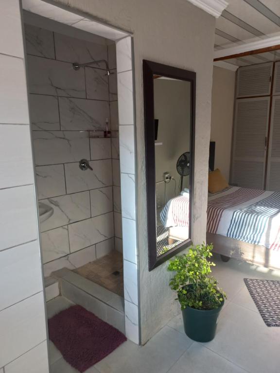 uma casa de banho com um chuveiro, um espelho e uma cama em Comfort place 2 em Pretoria