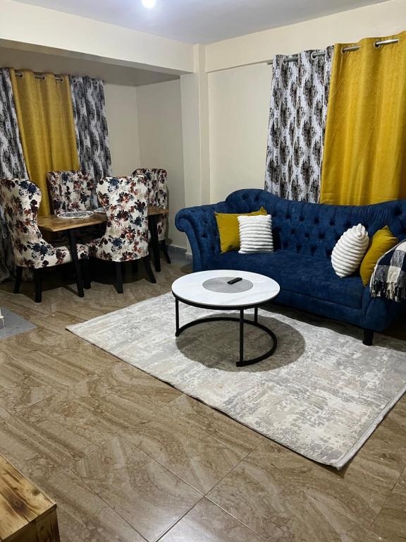 uma sala de estar com um sofá azul e uma mesa em Fully Furnished 2br Apartment King'ong'o Nyeri - Youngsky em Nyeri