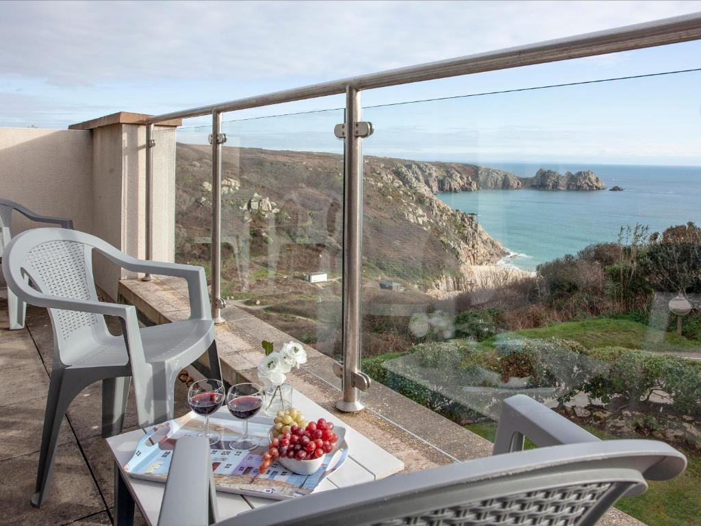 een tafel en stoelen op een balkon met uitzicht op de oceaan bij Cove View in Porthcurno