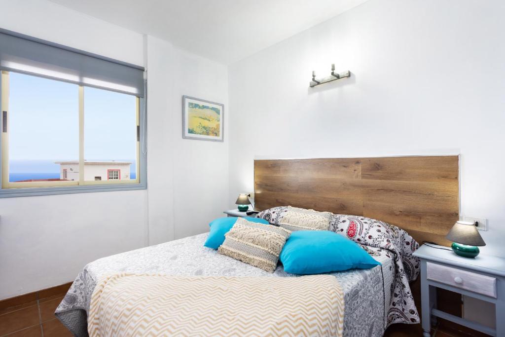 1 dormitorio con 1 cama con cabecero de madera en EDEN RENTALS Atogo Cozy Apartment en Granadilla de Abona