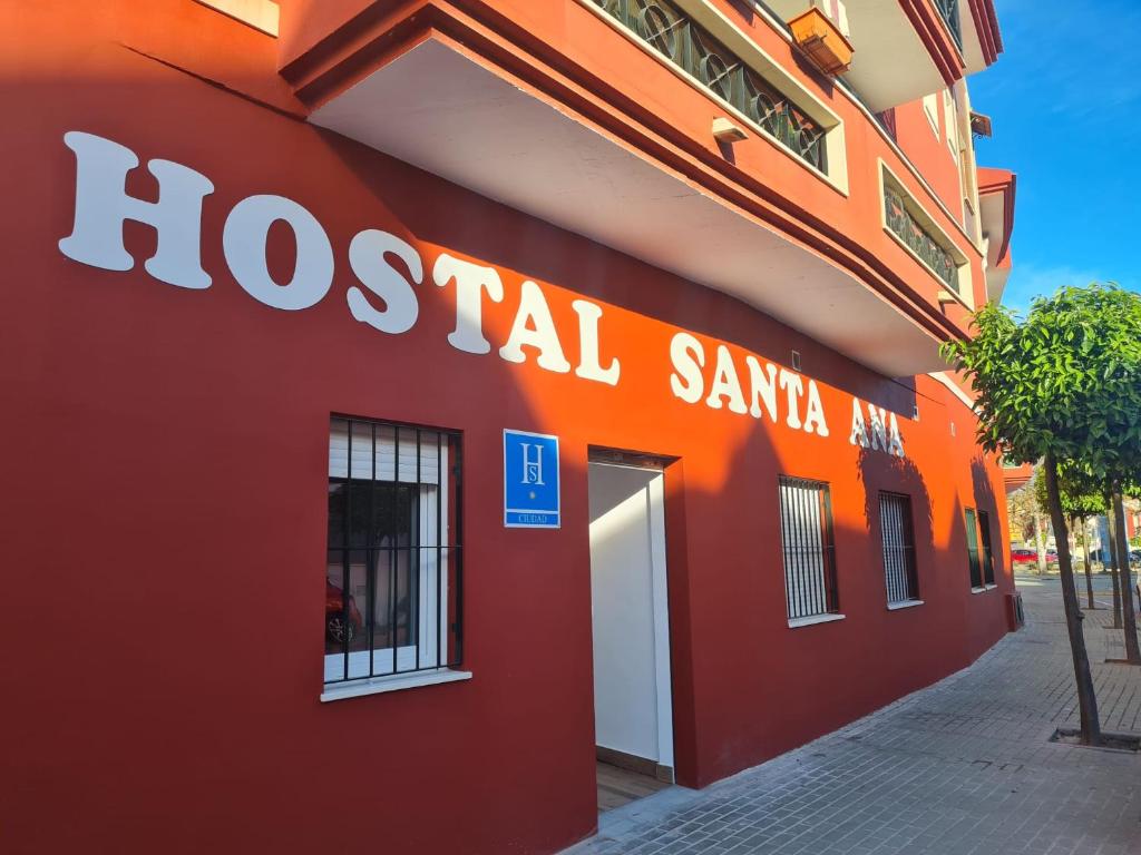 un edificio rojo con un letrero de santa hosocial en él en Hostal Santa Ana, en Huelva
