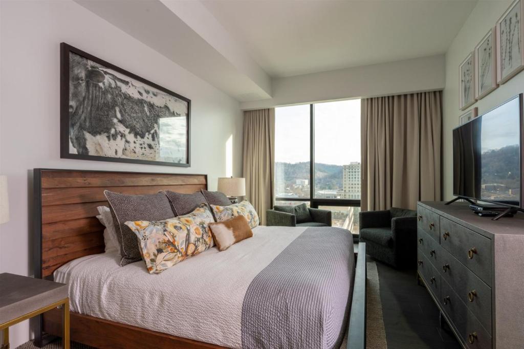 a bedroom with a bed and a desk and a television at 'The Views Over Pack Square Park' A Luxury Downtown Condo with Mountain and City Views at Arras Vacation Rentals in Asheville