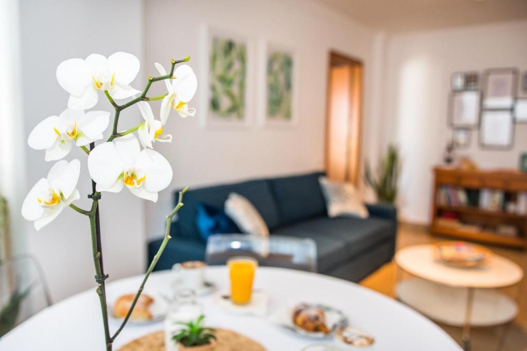 una sala de estar con una mesa con un jarrón de flores en House Canteras Castillo de la Luz, en Las Palmas de Gran Canaria