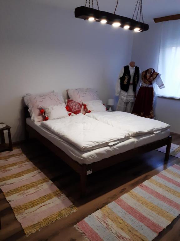 Una cama en una habitación con dos personas de pie junto a ella en Etno Ana, 