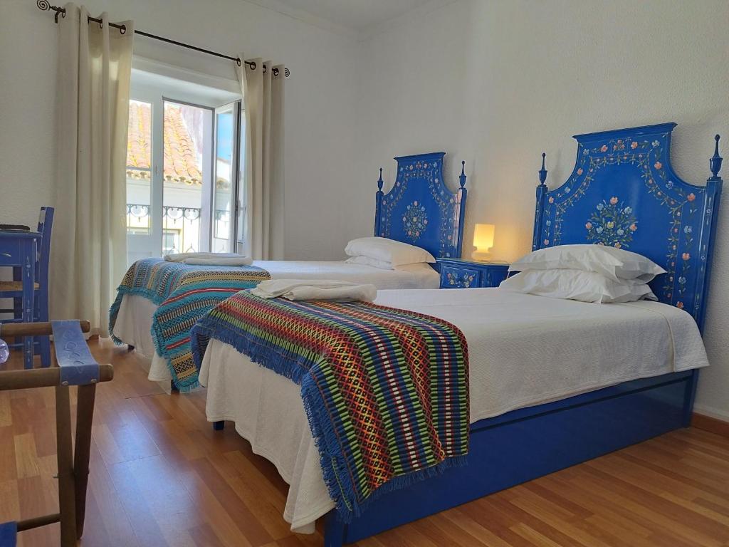 two beds with blue headboards in a bedroom at Mont' Sobro House Rooms in Évora